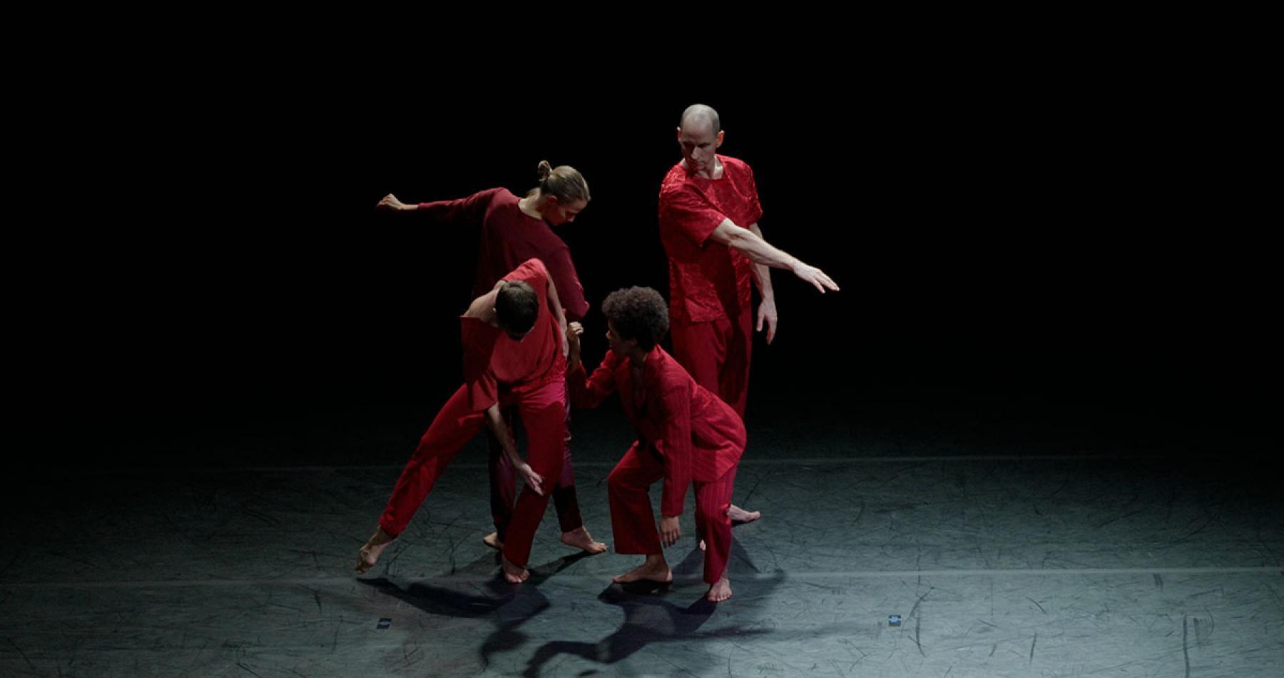 Four dancers in red on a stage
