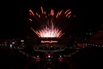 Fireworks explode behind a lit sign reading "Congratulations, Graduates!" in DKR Stadium for UT Commencement