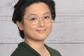A portrait of a person in glasses and a green shirt
