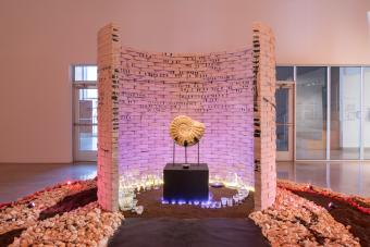 An alter with a shell fossil is at the center of a semi-circle brick wall in a museum gallery space