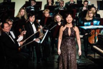 Hyeyoung Song stands in front of an orchestra 