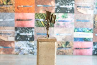 work of tiny bronze statue holding flag on top of compressed earth stand