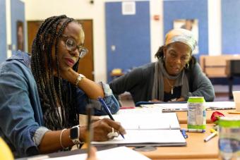 Dr. Lisa B. Thompson and a collaborator sit at a table, workshopping her new play