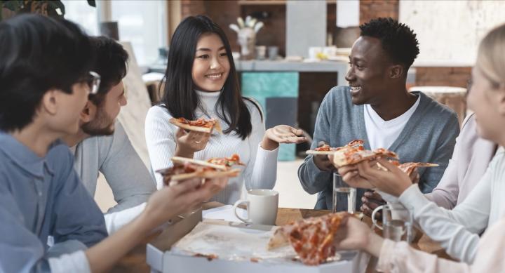 Students chat while eating pizza