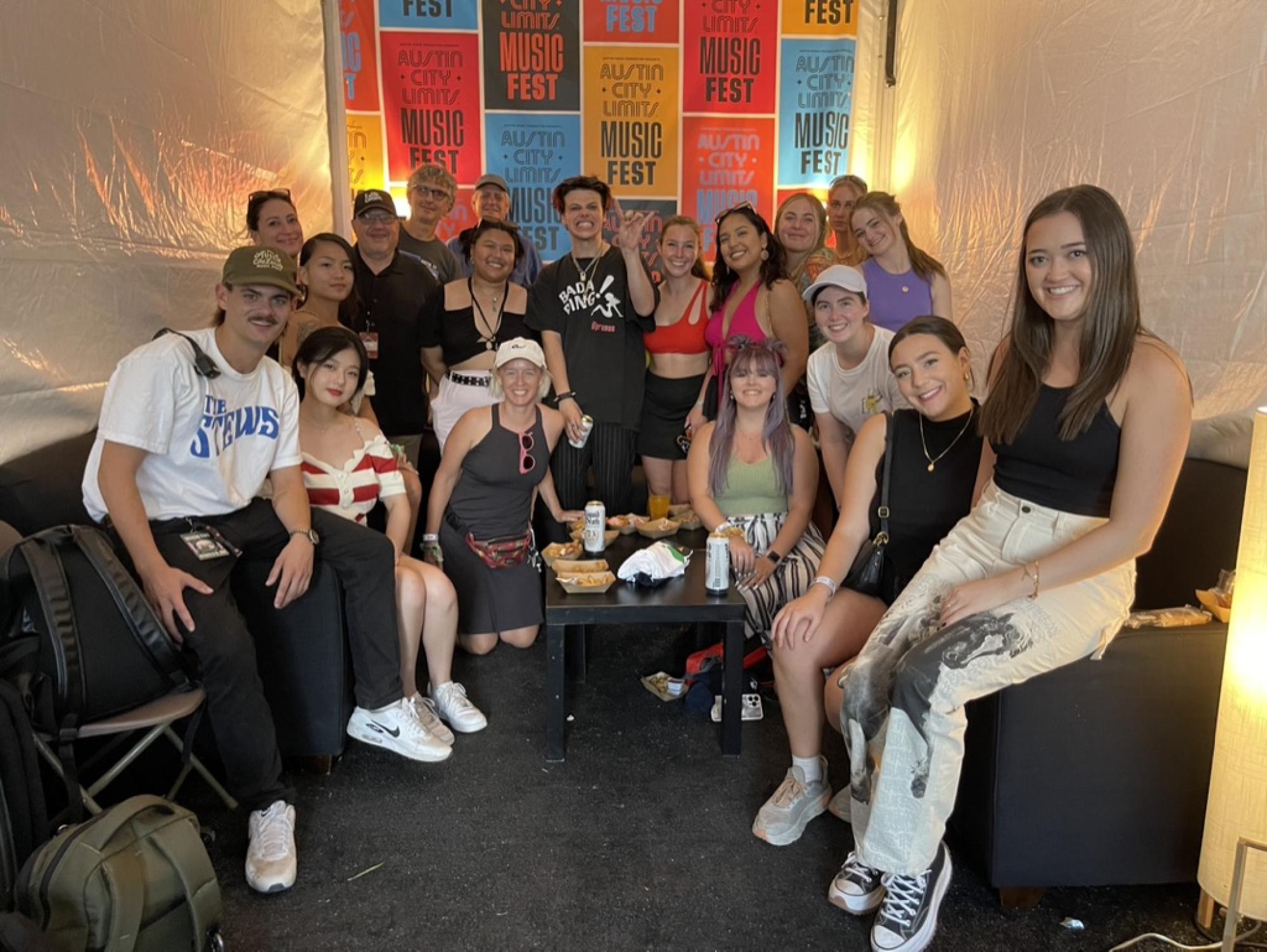 A group of students with their professors and a musician inside a tent at Austin City Limits Festival