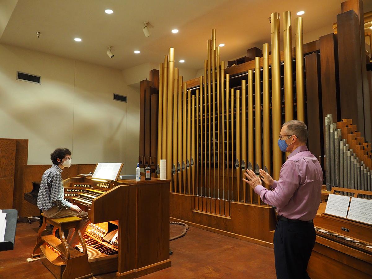 A college student in a mask in an organ rehearsal with his masked professor