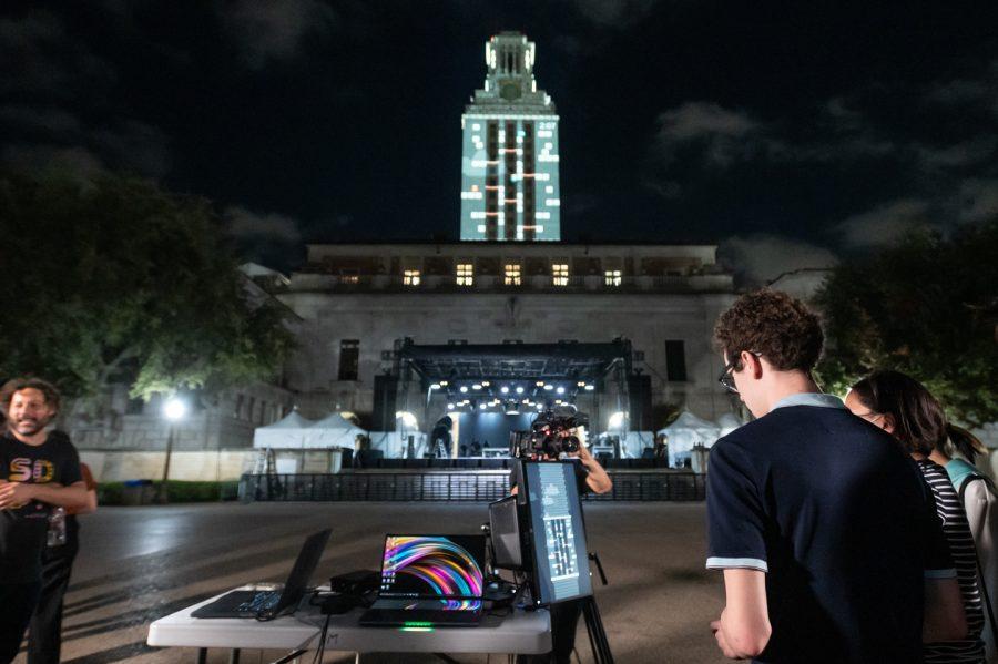 A video game is projected on the UT Tower with players in the foreground