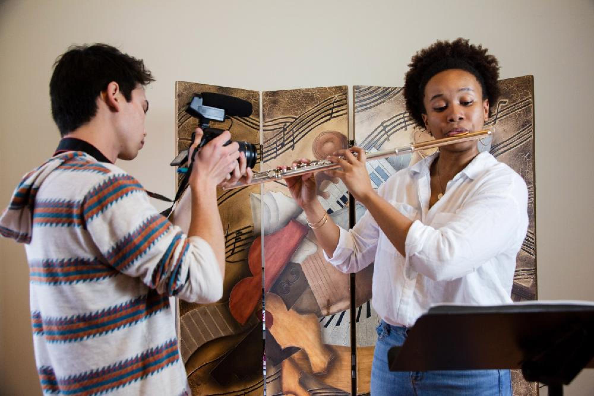 A videographer records a flute player performing a classical music piece