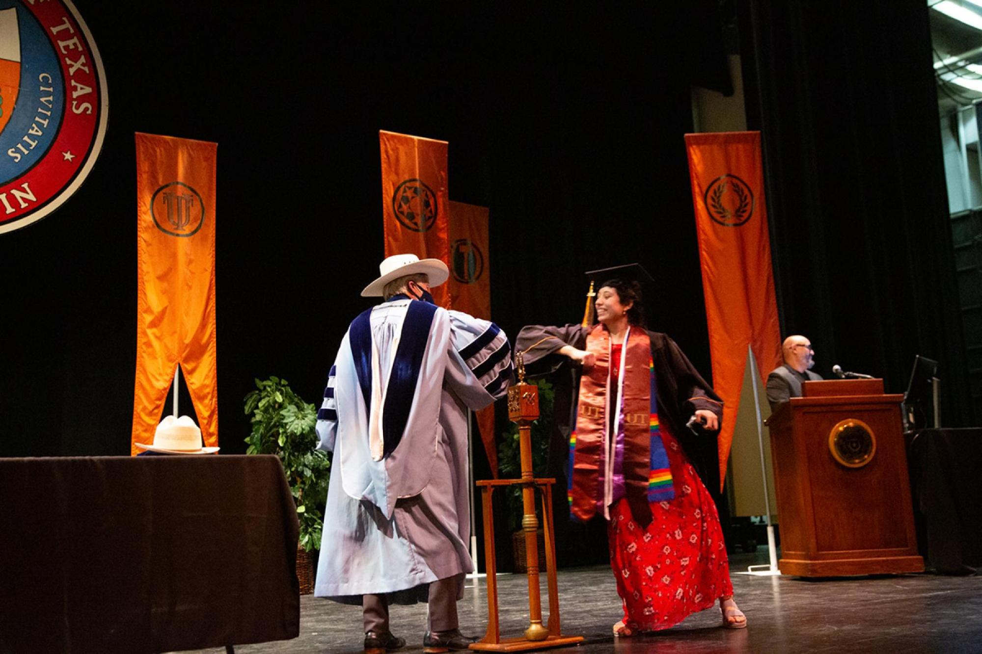 Dean Dempster and student touching elbows on stage