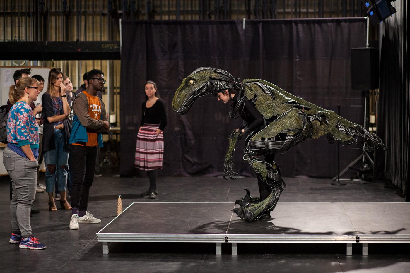 UT students examine an animatronic raptor costume worn by another student