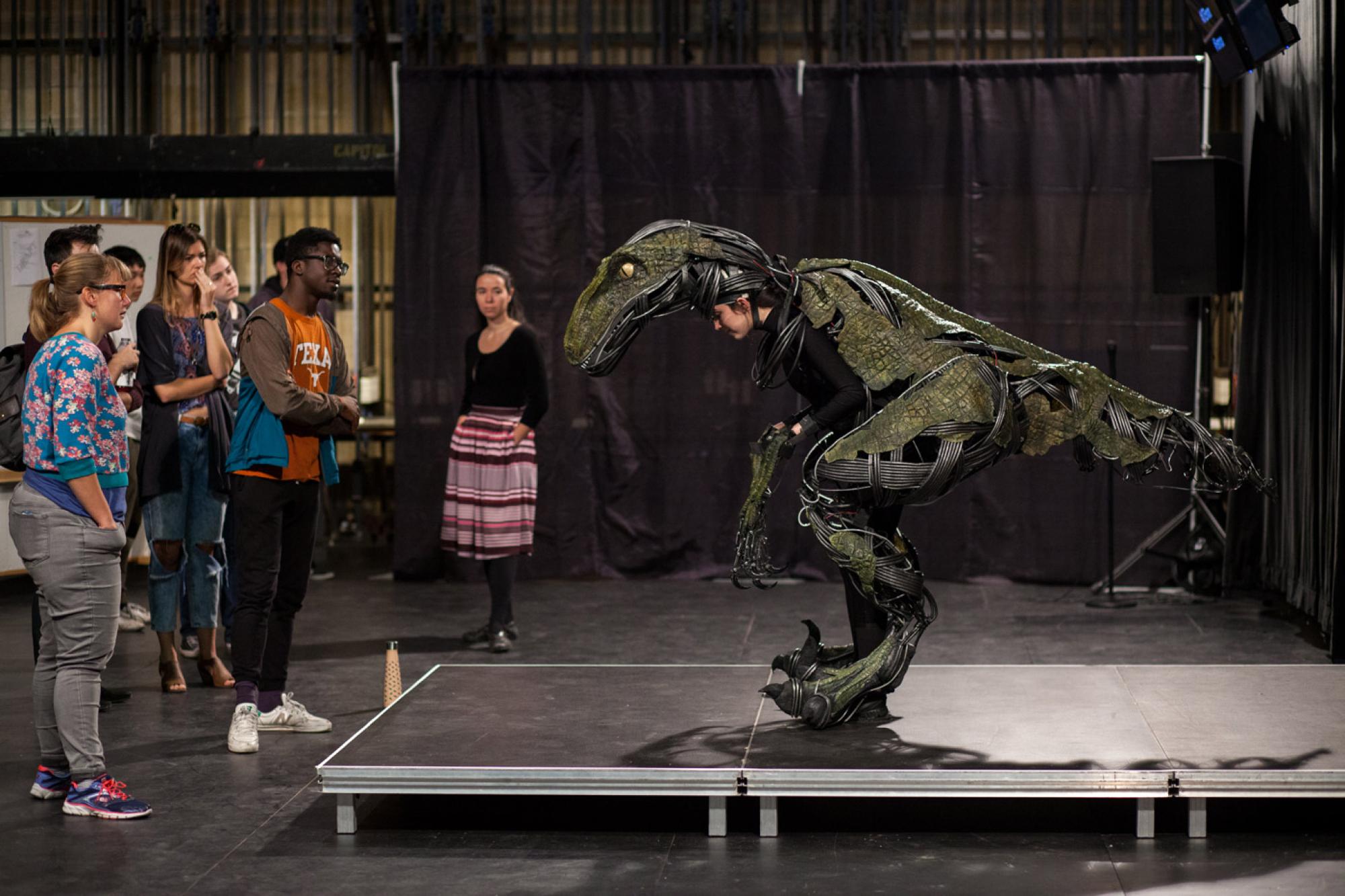 UT students examine an animatronic raptor costume worn by another student