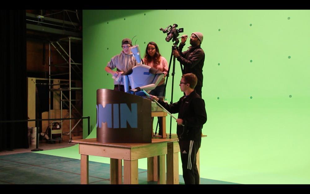 students maneuver a robot puppet in front of a green screen