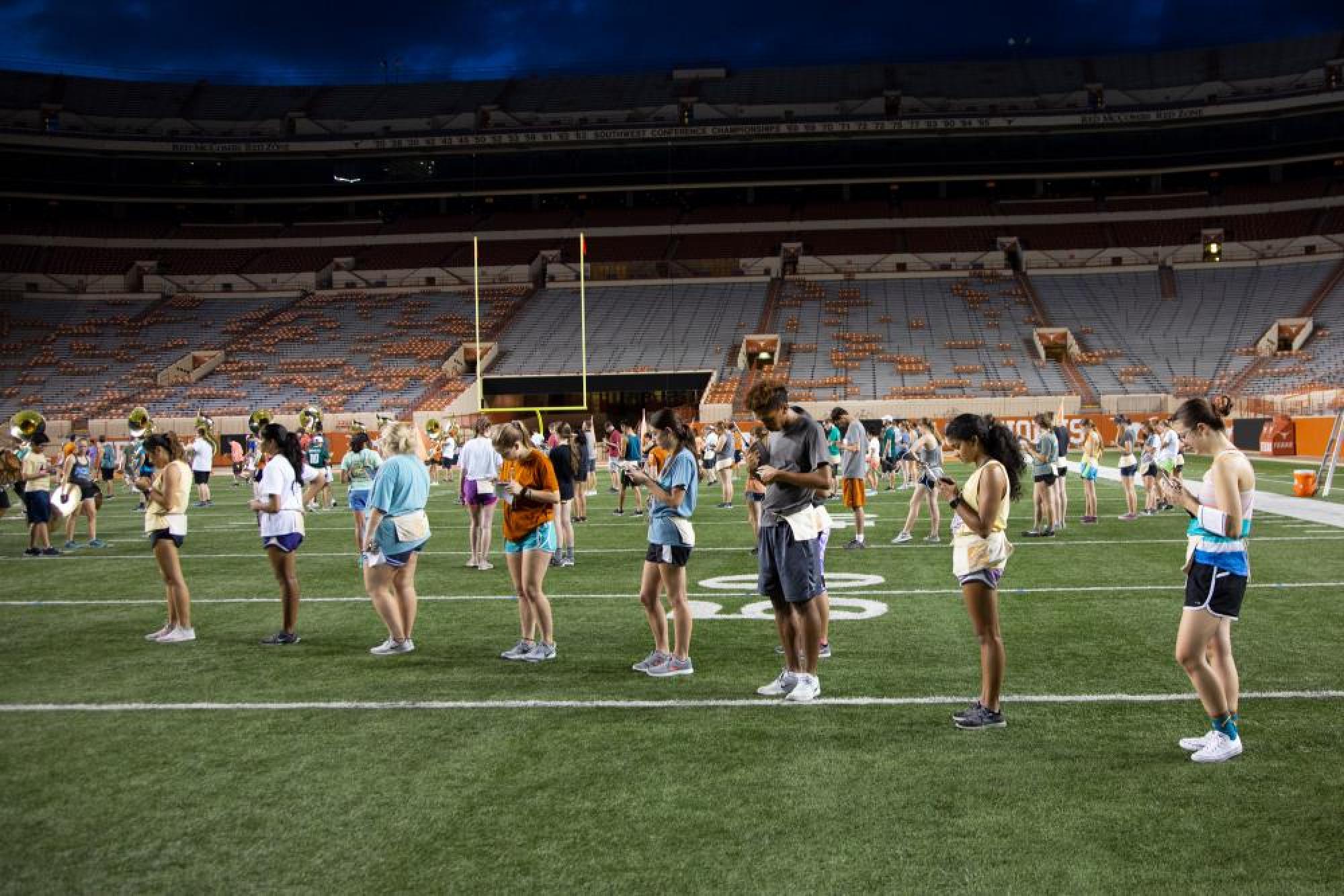 UT Longhorn Band members rehearsing on a football field