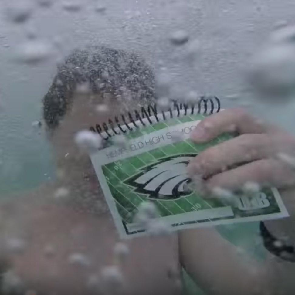 Luke Gall underwater with a drill book to show it's waterproof