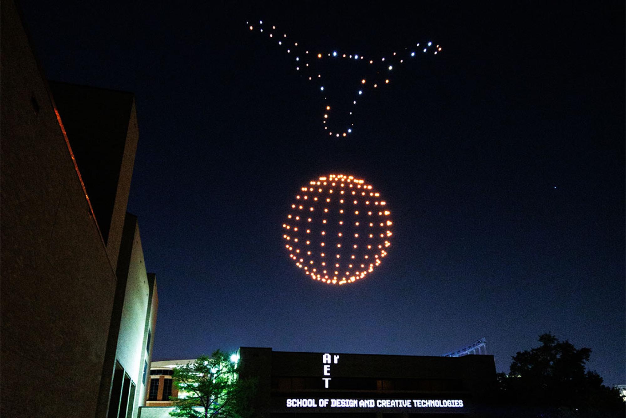 A student-created drone show with a formation a 3-D Longhorn over an orange sphere