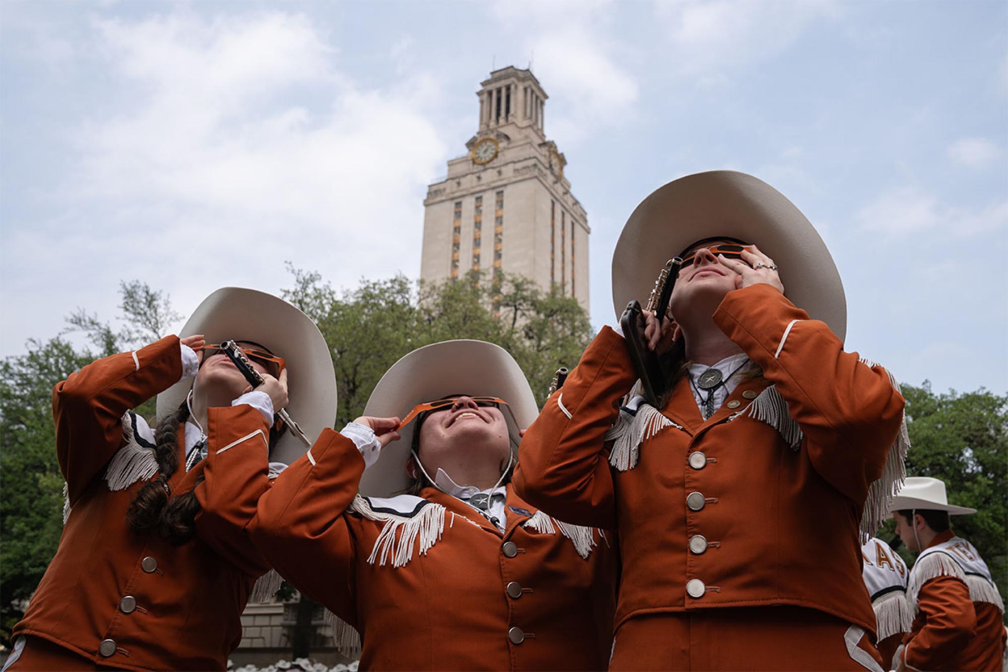 Longhorn Band members view the eclipse through special glasses in front of the UT Tower