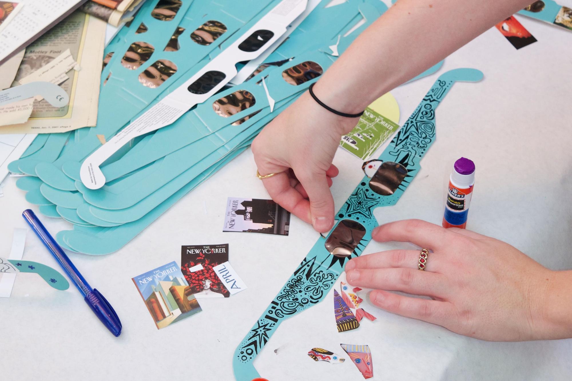 A student adds stickers to customize a pair of eclipse sunglasses