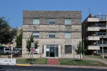 A gray three-story cinderblock building with glass doors