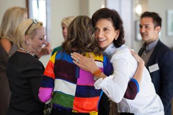 A member of the Fine Arts Advisory Council embraces another member at a meeting