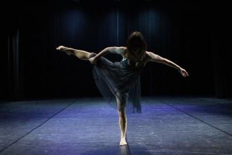 A dancer balances on one foot on a stage