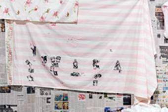 an image of black ink block artwork on a sheet, hanging on a laundry line 