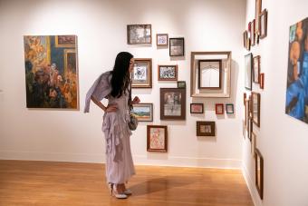 A student views framed artworks in a gallery