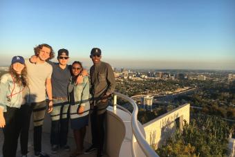 Five students pose on a balcony of the Getty Center with the Los Angeles skyline in the background