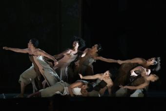 Six dancers perform on stage during the world premiere opera INTELLIGENCE, five leaning back while one reaches forward