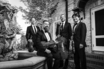 Black and white photo of the Miró Quartet by a fountain.