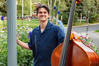 Aidan Berg standing in a park holding a standup bass