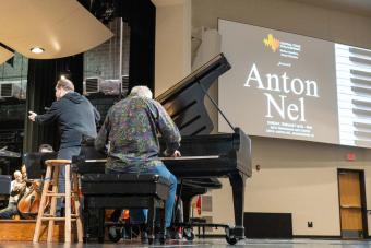 Anton Nel Playing the piano on the stage with a screen behind him that says &quot;Anton Nel&quot;
