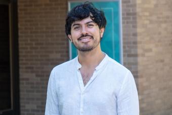 Daniel Ruiz Bustos smiling in front of a brick building