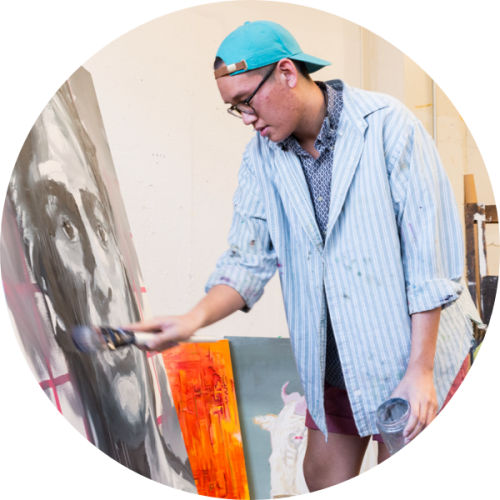 A student painting in front of an easel.