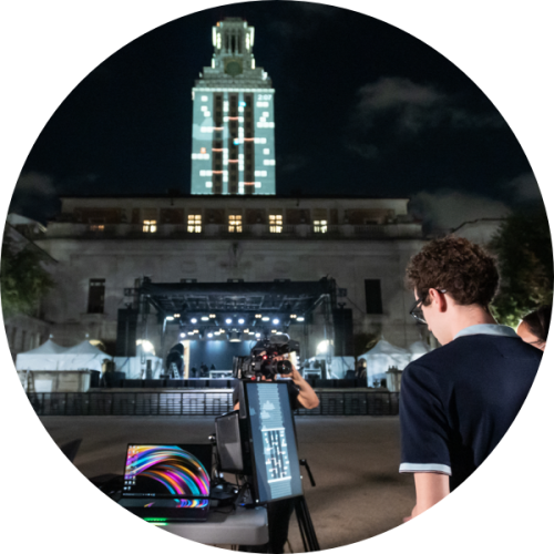 A video game is projected on the UT Tower as participants play the game. 