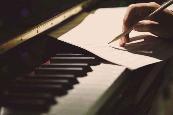 a composer works on a musical score at a piano