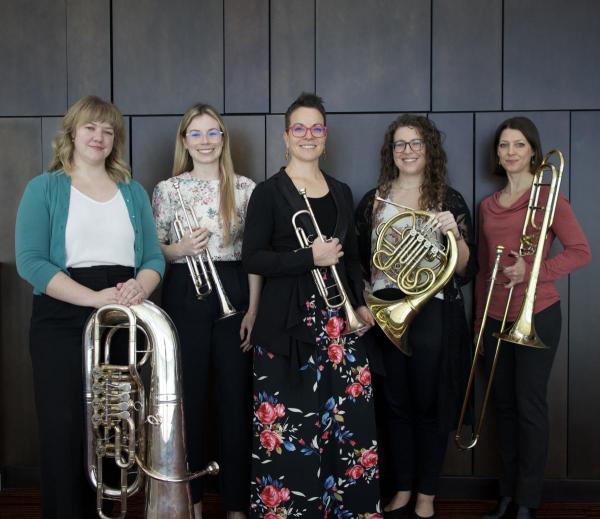 Members of the Magnolia Brass Quintet holding their instruments and smiling.