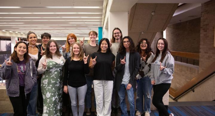 A group of students gives the Hook'em hand gesture