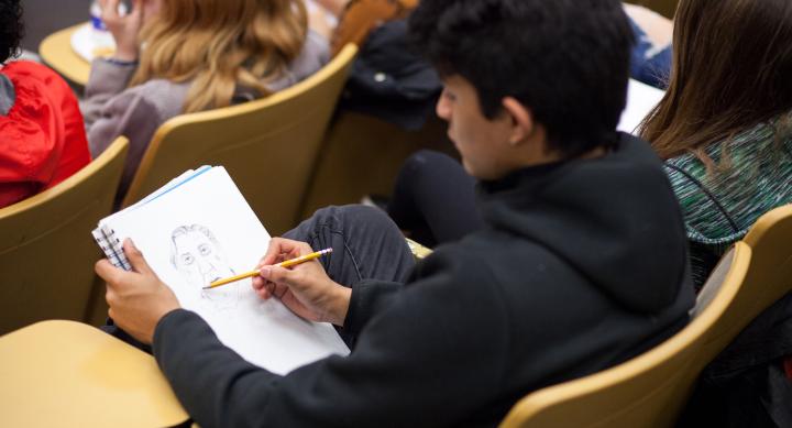 A student sketches the speaker in a classroom