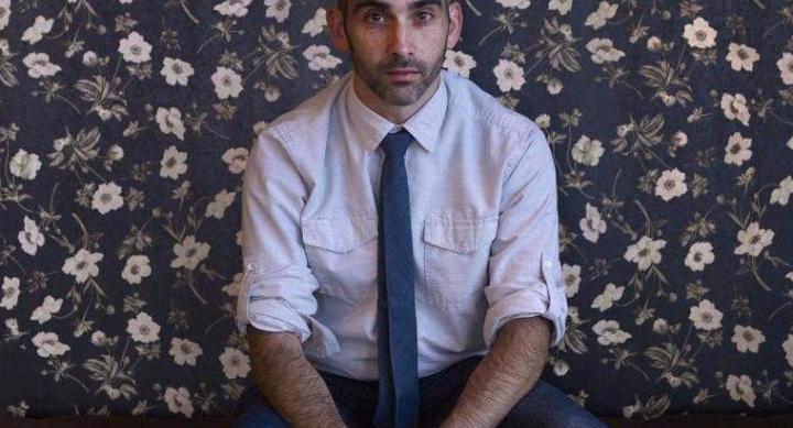 Michael Wellen sits in front of a floral wall