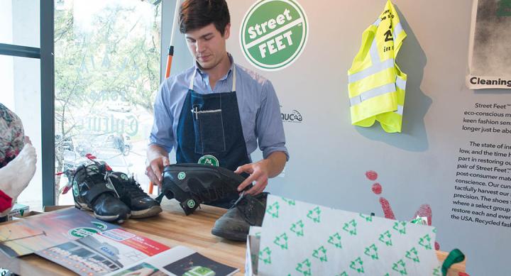 Henry Smith works on shoes as part of an art exhibition.