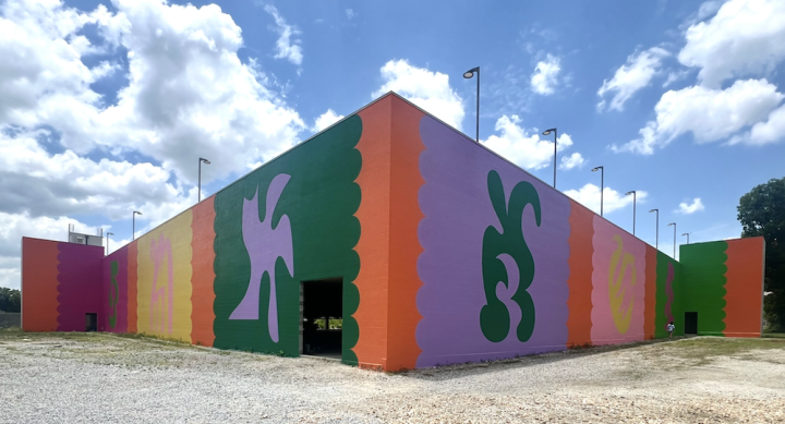 Carlos Rosales-Silva's public mural on the parking garage of The Momentary in Bentonville, Arkansas uses bright colors with figures in opposite color configurations.