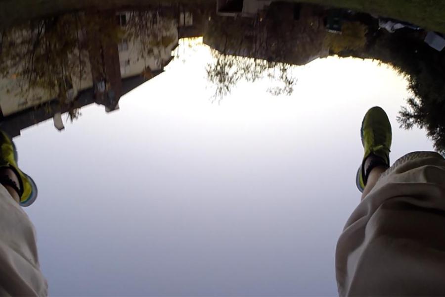 composite image of human legs and feet shown above reflection of water in landscape