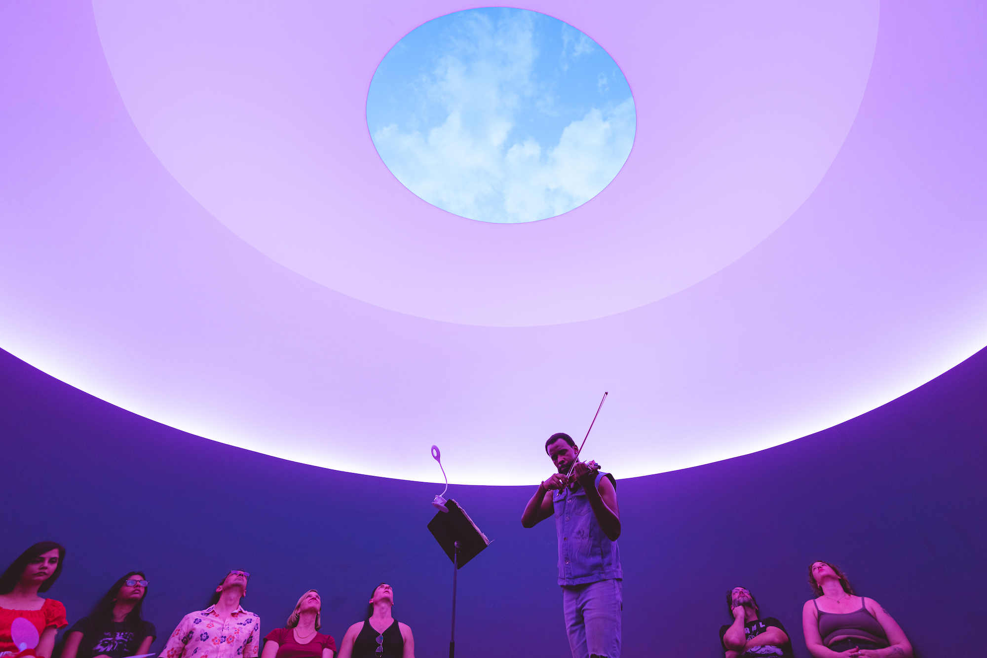 A musician plays a violin inside The Color Insider, a James Turrell Skyspace at UT Austin