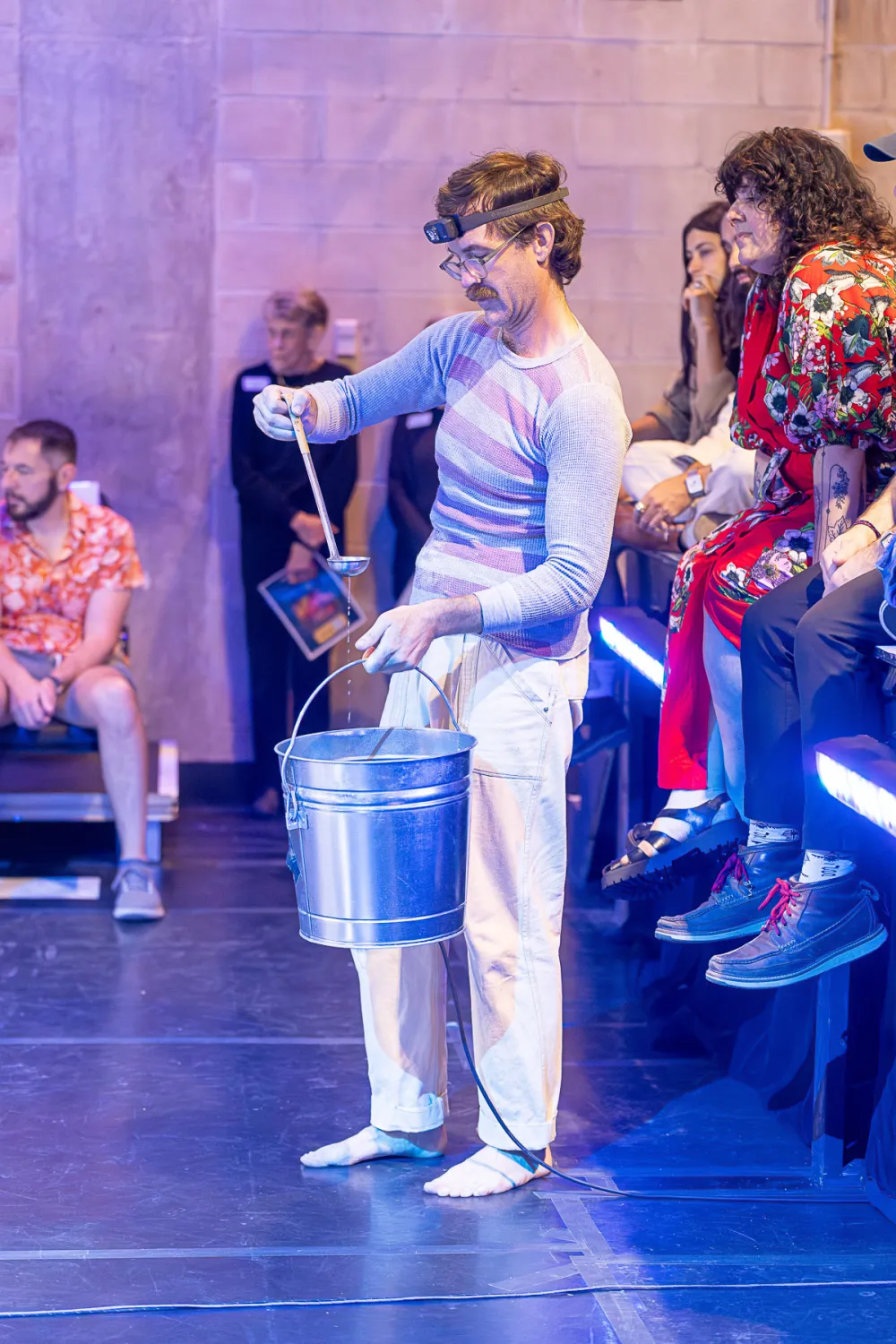 Rude Mechs member Thomas Graves creates rain with a ladle and metal bucket in a performance of "Not Every Mountain"