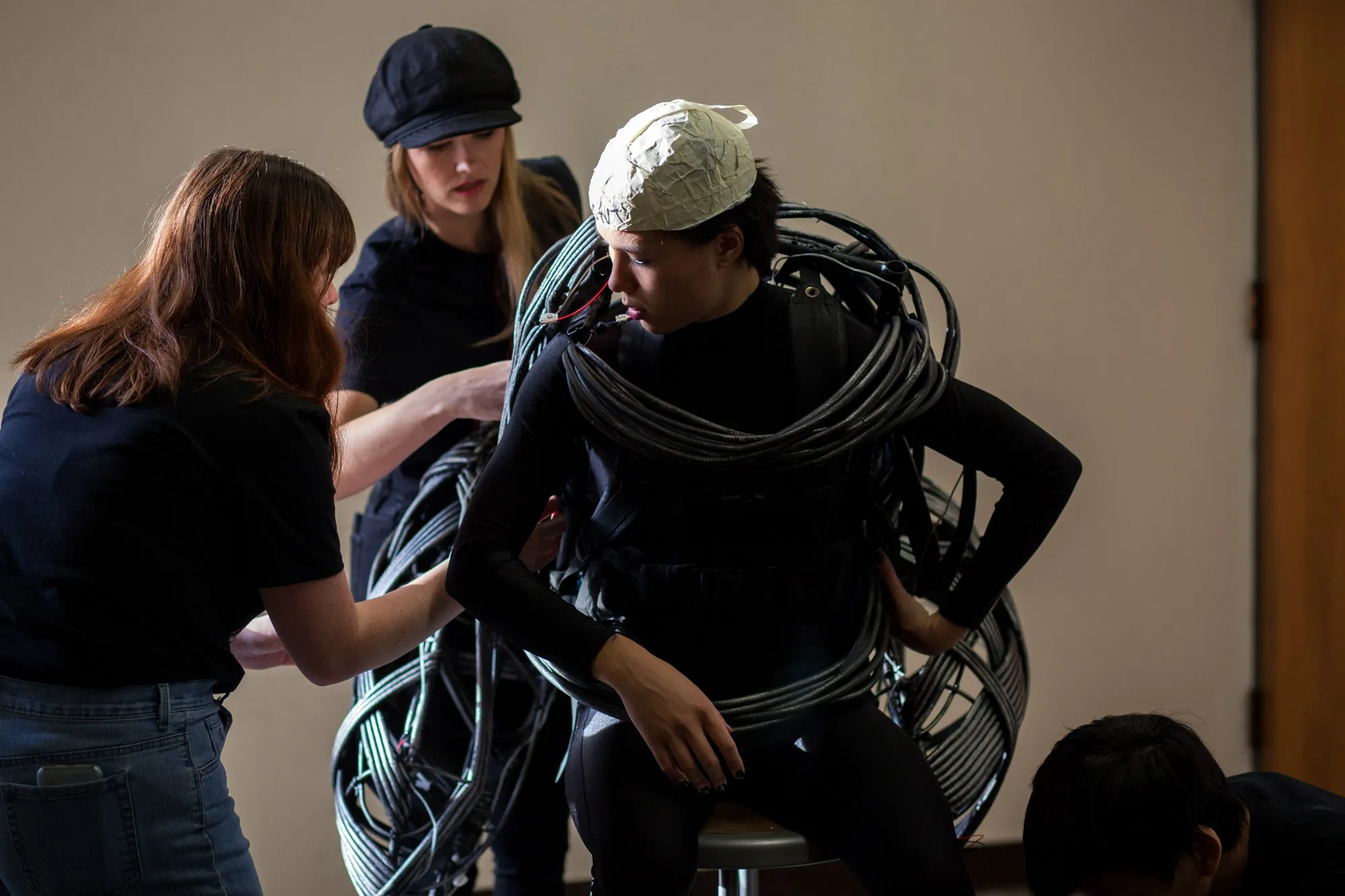Students help dress an actor in a raptor costume