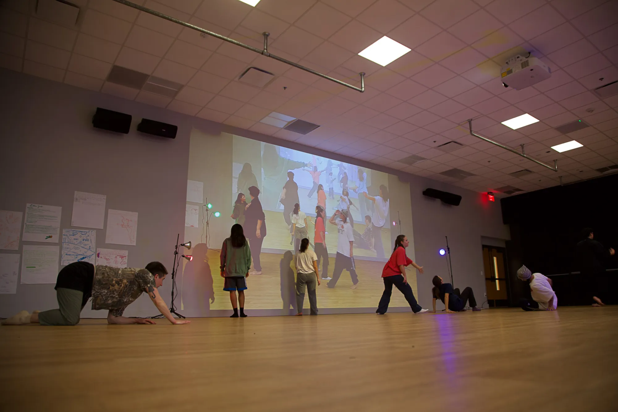 Dance students rehearse in a studio with projected imagery on the wall behind them
