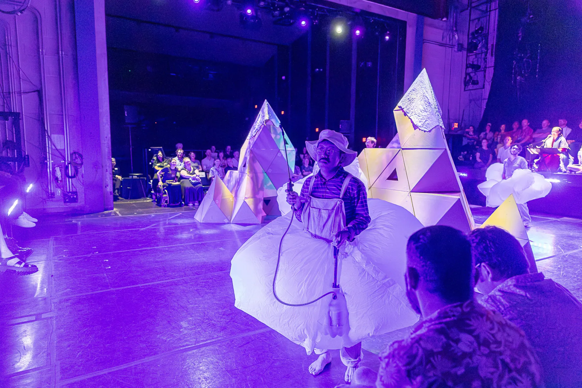 A performer spritzes audience members with rainwater during a Rude Mechs performance of "Not Every Mountain"