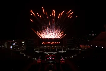 Fireworks explode behind a lit sign reading "Congratulations, Graduates!" in DKR Stadium for UT Commencement