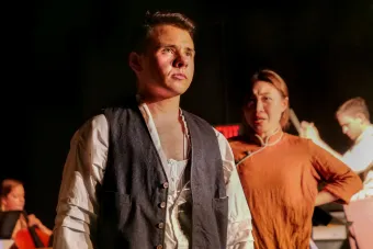 The Barmaid (Chang Liu) sings to Charley (Holden Madagame). Composer Keith Allegretti conducts. Photo by Logan Smith.