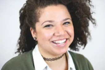 A photo of Felicia Fitzpatrick. Felicia has long brown curly hair and is wearing a green sweater